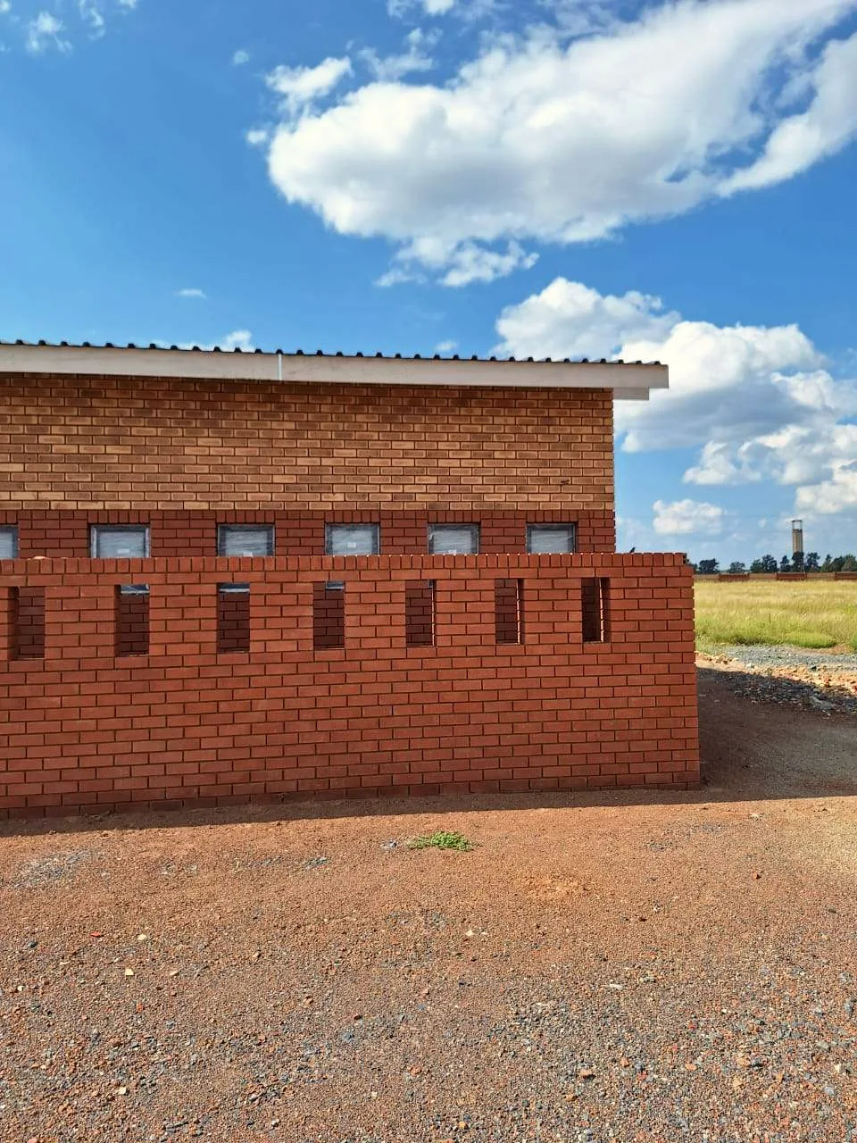 Completed face-brick building under a blue sky