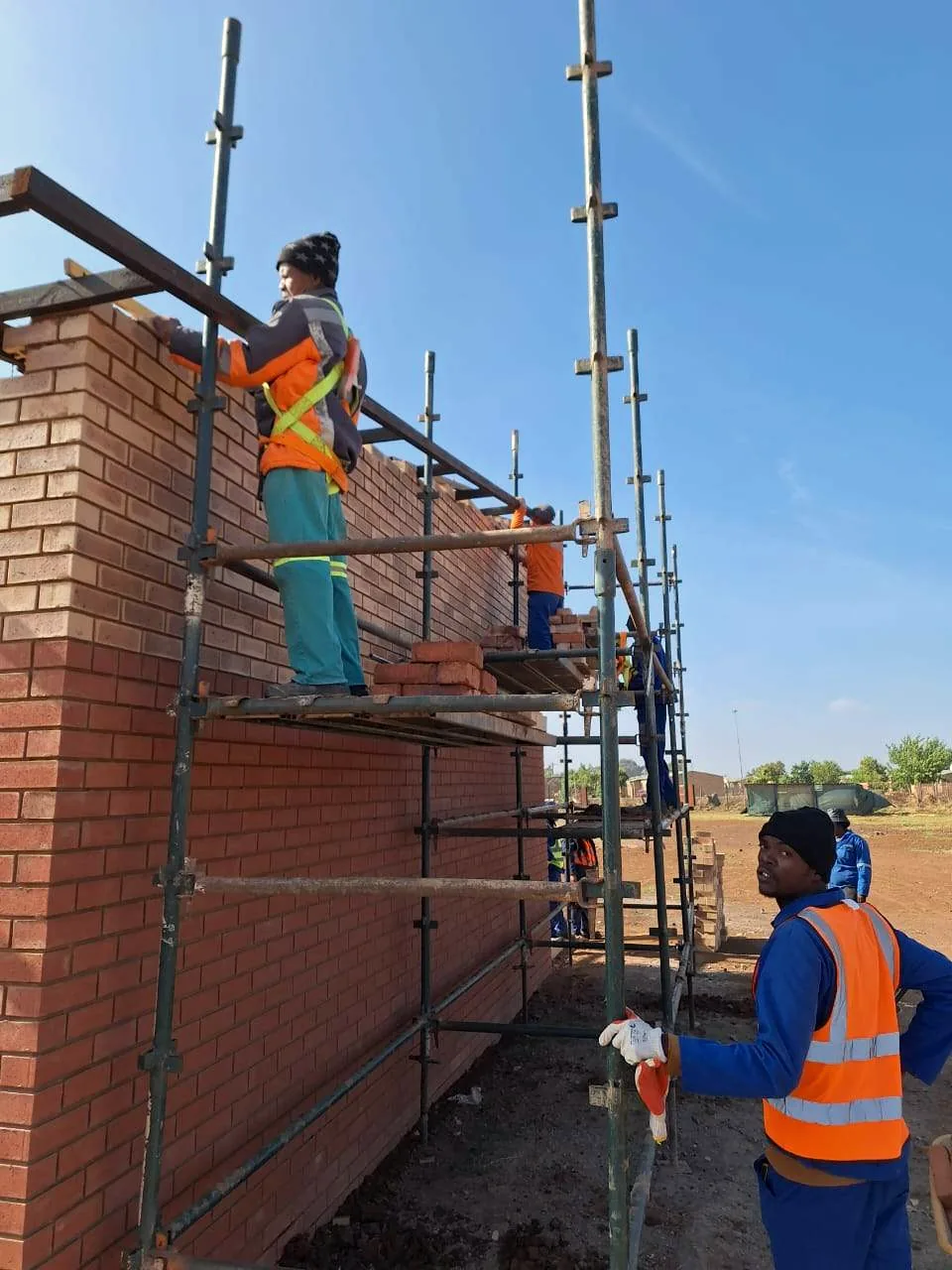 Hlwella bricklayers in PPE working from scaffolding