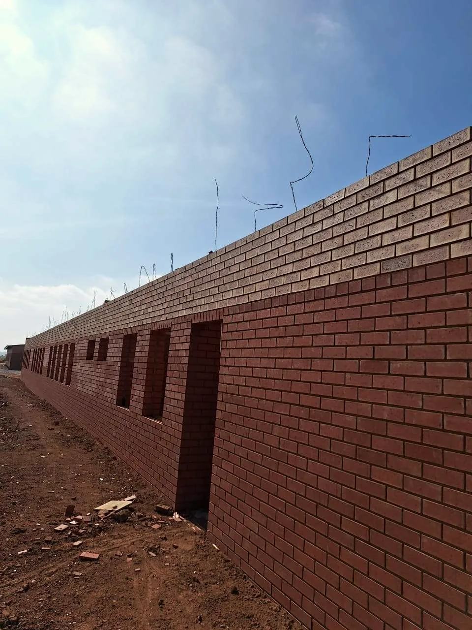 Long face-brick boundary wall built by Hlwella